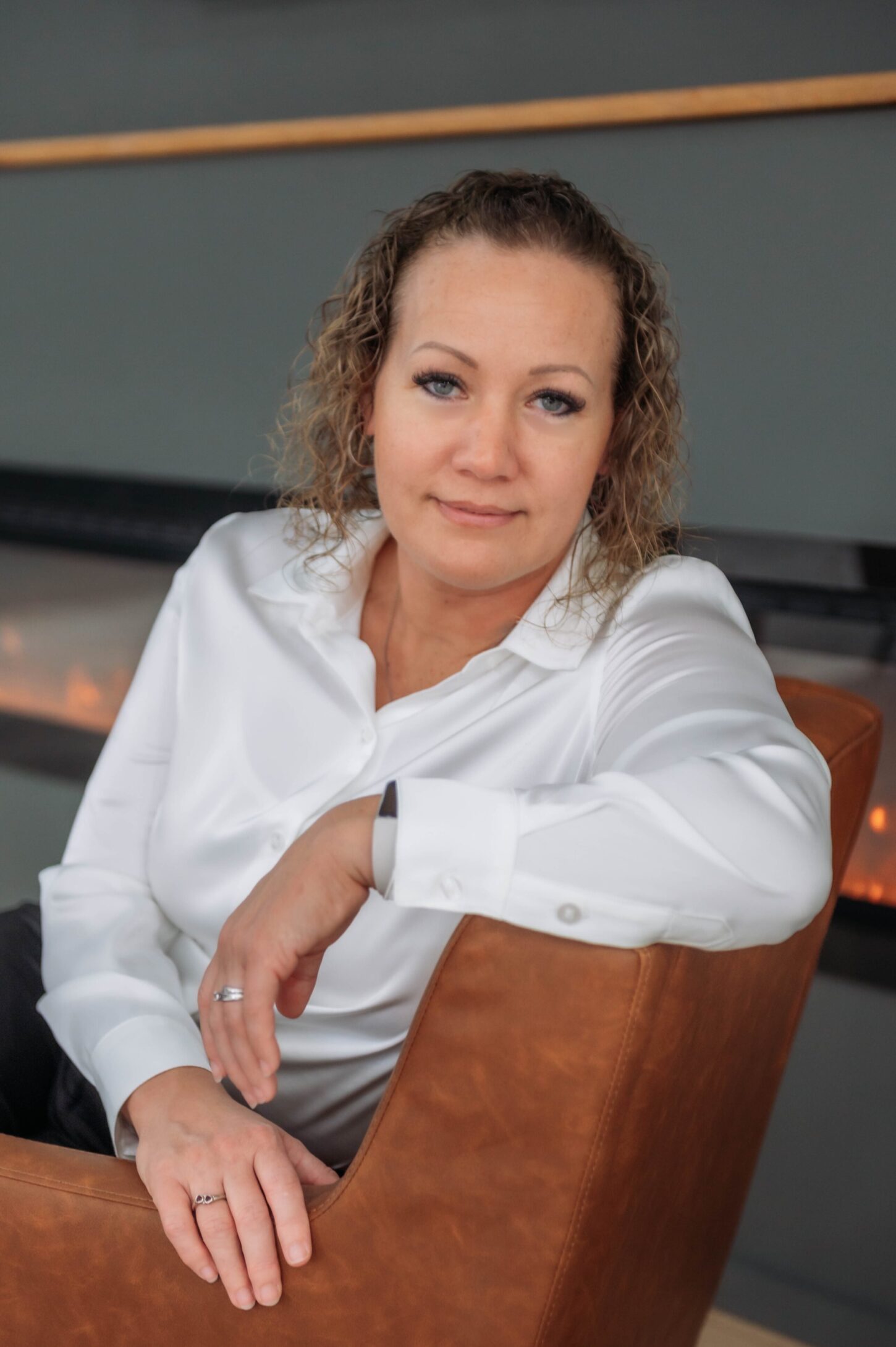 A woman sitting in front of a fireplace.